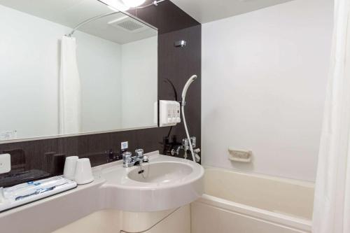 ein Bad mit einem Waschbecken und einem Spiegel in der Unterkunft Comfort Hotel Kariya in Kariya
