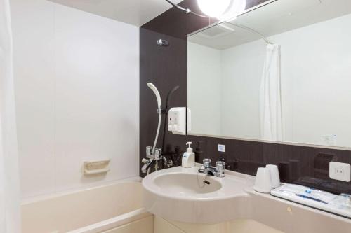 W łazience znajduje się umywalka i lustro. w obiekcie Comfort Hotel Kushiro w mieście Kushiro