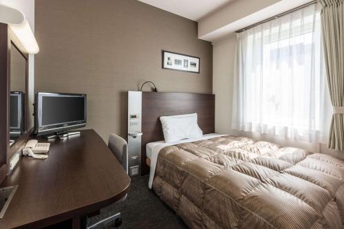 釧路市にあるコンフォートホテル釧路のベッドとデスクが備わるホテルルームです。