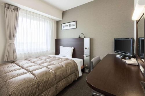 八戸市にあるコンフォートホテル八戸のベッド、デスク、コンピュータが備わるホテルルームです。