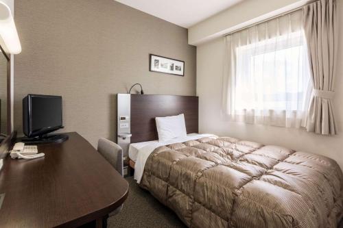Habitación de hotel con cama y escritorio con ordenador en Comfort Hotel Kitakami, en Kitakami