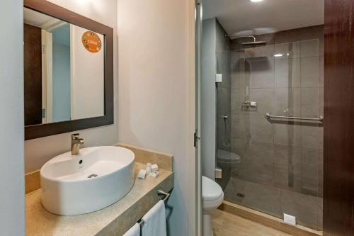 a white bathroom with a sink and a shower at Sleep Inn Tijuana in Tijuana