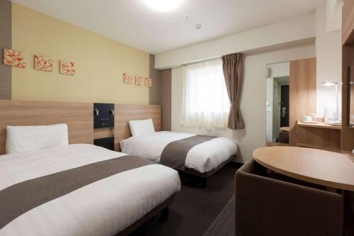 Comfort Hotel Wakayama في واكاياما: غرفة فندقية بسريرين وطاولة