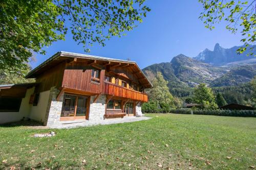 uma casa num campo com montanhas ao fundo em Chalet du Golf 618 - Happy Rentals em Chamonix-Mont-Blanc