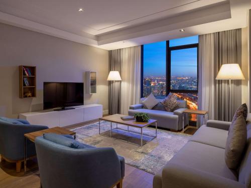 Movenpick Living Istanbul West في إسطنبول: غرفة معيشة مع أريكة وتلفزيون
