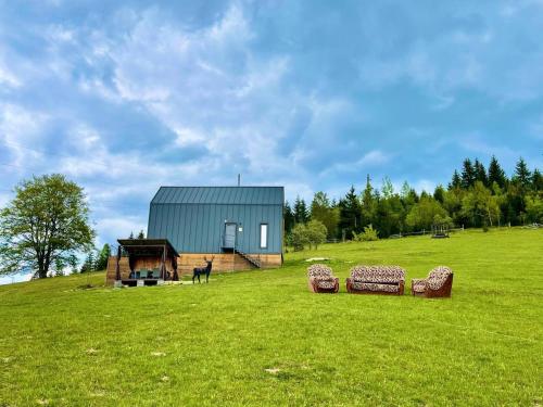 a house on a hill with a green field with two hay bales at Карпати Плай Village in Bukovel