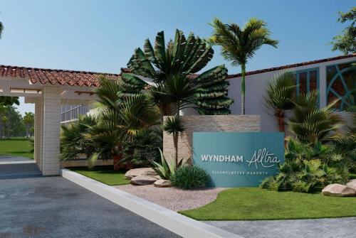 a sign in front of a building with palm trees at Wyndham Alltra Samana All Inclusive Resort in Las Galeras