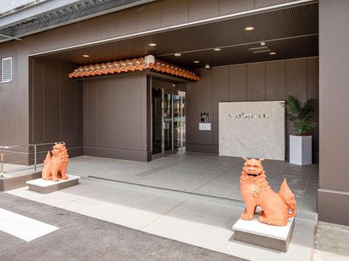 dos estatuas de gatos frente a un edificio en Comfort Hotel Ishigaki Island en Isla Ishigaki