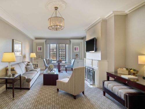 a living room with a couch and a tv at Fairmont Copley Plaza in Boston