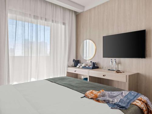a bedroom with a bed with a television on the wall at Mercure Larnaca Finikoudes Beach in Larnaka
