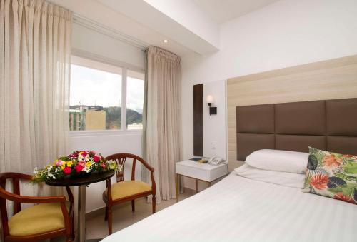 una habitación de hotel con una cama y una mesa con flores. en Hotel Faranda Express Soloy and Casino, a member of Radisson Individuals, en Panamá