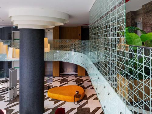 een lobby met een gele bank en een glazen wand bij ibis Styles Istanbul Merter in Istanbul
