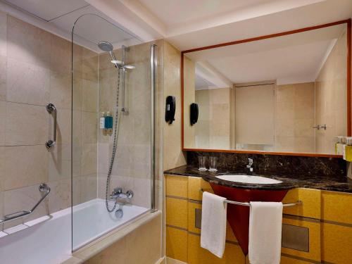 a bathroom with a shower and a sink and a tub at Queen Elizabeth 2 Hotel in Dubai