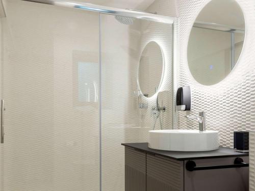 uma casa de banho com um chuveiro, um lavatório e um espelho. em Aparthotel Adagio Malta Central em Msida
