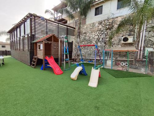 a playground with slides and a swing set at צמרת הצימרים - צימרים מקסימים עם בריכה משותפת מחוממת וג'קוזי פרטי in Dāliyat el Karmil
