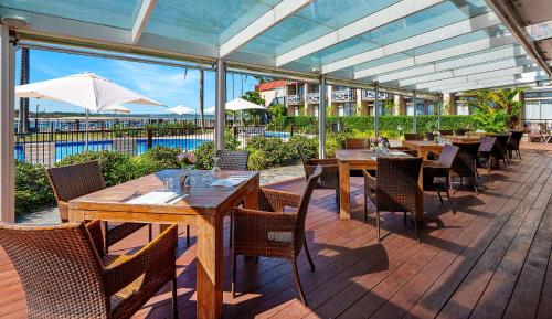 a patio with tables and chairs and an umbrella at Comfort Resort Waters Edge in Port Macquarie