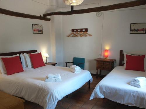 um quarto com 2 camas com almofadas vermelhas e brancas em Cortijo mirasol em Santa Cruz de Comercio
