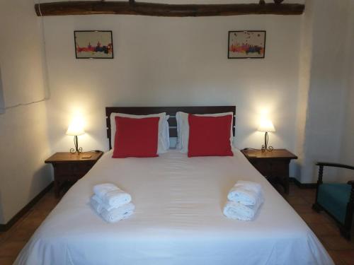 1 dormitorio con 1 cama blanca grande con almohadas rojas en Cortijo mirasol, en Santa Cruz de Comercio