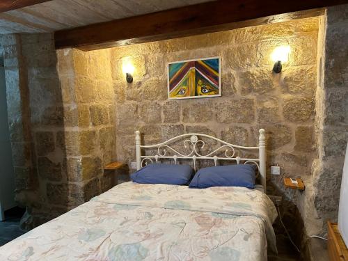 sypialnia z łóżkiem w kamiennej ścianie w obiekcie Historic Townhouse in Birgu Center w mieście Vittoriosa
