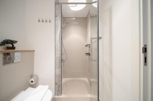 a white bathroom with a shower and a toilet at First Class Apartments in Dubai Hills - Next to Dubai Hills Mall - Socio, Collective and Golfville Towers in Dubai
