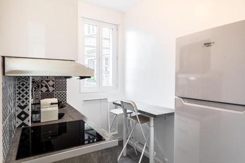 - une cuisine blanche avec un comptoir et un réfrigérateur dans l'établissement GuestReady - A precious gem near Paris, à Asnières-sur-Seine