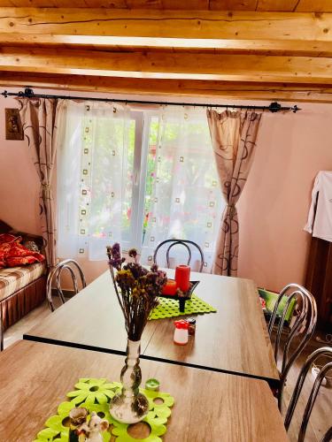 a dining room table with a vase of flowers on it at Balla House in Tărcaia