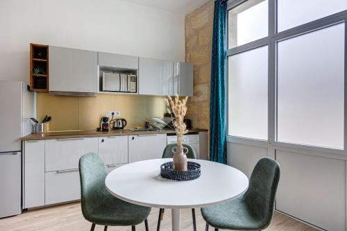uma cozinha com uma mesa branca e cadeiras verdes em GuestReady - Stylish Haven in Downtown Bordeaux em Bordeaux