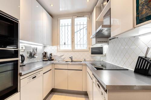 une cuisine blanche avec un évier et une fenêtre dans l'établissement GuestReady - A Slice of Parisian Paradise, à Paris