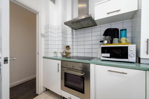 una cucina con piano cottura e forno a microonde di GuestReady - Petite Perfection near Battersea Park a Londra