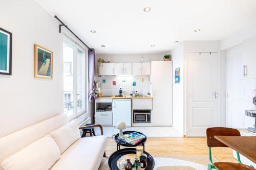 un salon avec un canapé blanc et une cuisine dans l'établissement GuestReady - Comfortable Cocoon near le Marais, à Paris
