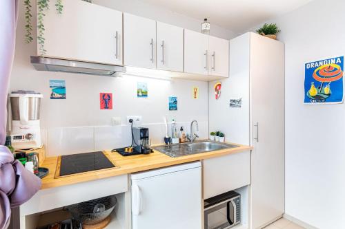 une cuisine avec des armoires blanches et un évier dans l'établissement GuestReady - Comfortable Cocoon near le Marais, à Paris