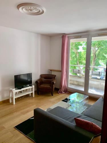 a living room with a couch and a television at Appartement vue sur Lac proche métro in Créteil