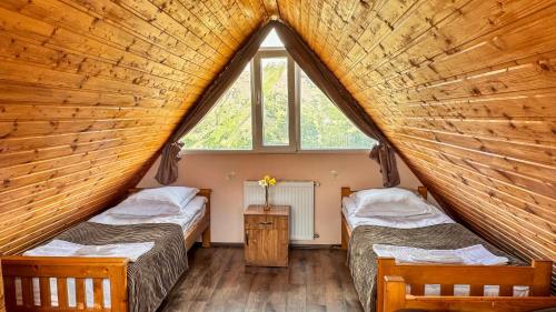 2 Betten in einem Zimmer mit einem großen Fenster in der Unterkunft Cottage Gudauri in Gudauri