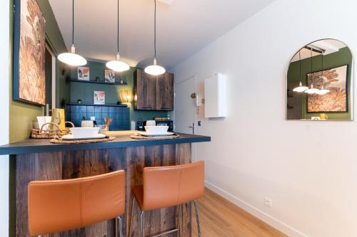 - une cuisine avec un comptoir en bois et des chaises orange dans l'établissement Cocon Coloré - Studio pour 2 30min de Paris, à Chevilly-Larue