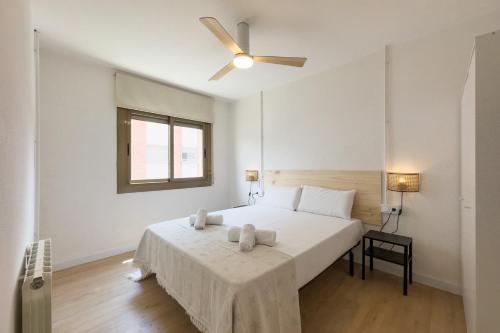 a bedroom with a white bed with a ceiling fan at Bed&BCN Forum II in Sant Adria de Besos