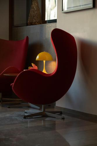 a red chair next to a table with a lamp at Avalon Hotel in Gothenburg