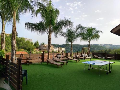 a playground with a ping pong table and palm trees at צמרת הצימרים - צימרים מקסימים עם בריכה משותפת מחוממת וג'קוזי פרטי in Dāliyat el Karmil