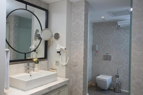 a bathroom with a sink and a mirror and a toilet at Fame Residence Kemer & Spa in Kemer