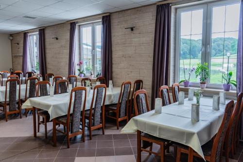 a dining room with tables and chairs and windows at Penzion ob Ribniku in Podlehnik