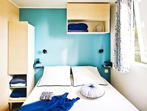 Schlafzimmer mit einem Bett mit blauer Wand in der Unterkunft Mobilhome 3 étoiles - efb0fi in Canet-de-Salars