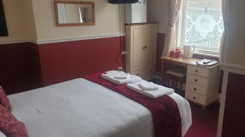 a bedroom with a bed and a desk and a window at All Seasons Guest House in Great Yarmouth