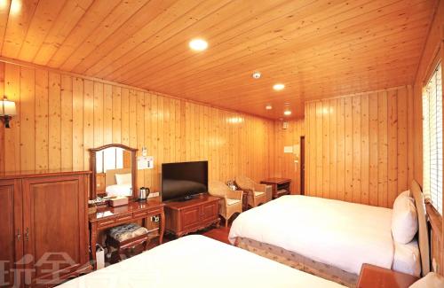 仁愛鄉的住宿－清境 百里莊園 Baili Manor Cing Jing，一间卧室配有两张床和电视。