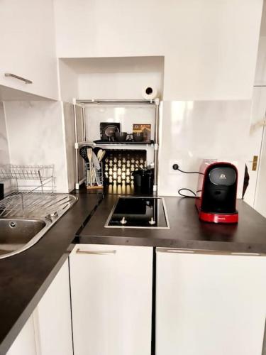 une cuisine avec des armoires blanches et un appareil rouge sur le comptoir dans l'établissement Bonito y Ambientado 10 AA1, à Paris