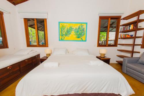 a bedroom with two beds and a couch and windows at Casa Yosi, Beach Front Piece of Heaven in San Juan del Sur