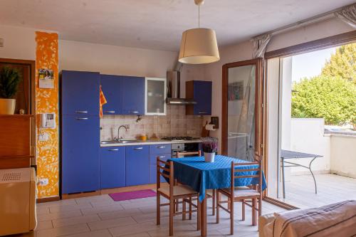 una cucina con mobili blu e un tavolo con sedie di Appartamentino a Susegana a Susegana