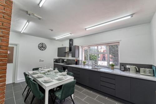 una cocina con mesa blanca, sillas, mesa y barra en Guest Homes - Chester House Retreat, en Kidderminster