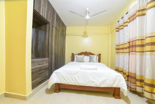 a bedroom with a bed with a wooden headboard at MAXIMILIAN HOMES in Kilifi