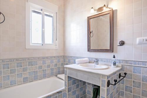 un bagno con un lavandino, una vasca e uno specchio di Chalet Villa Ariza a Cadice