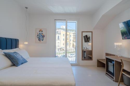 ein weißes Schlafzimmer mit einem großen Bett und einem Fenster in der Unterkunft Dimore delle Zagare Molo in Syrakus