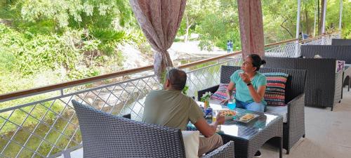 a man and a woman sitting at a table on a balcony at Hiranya Nature Retreat in Daulatābād